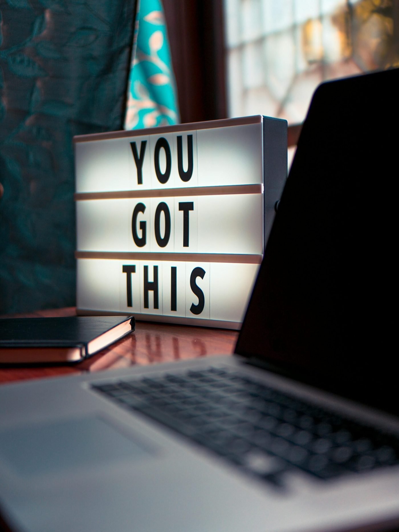 Illuminated lightbox with a motivational quote beside a laptop, promoting productivity.